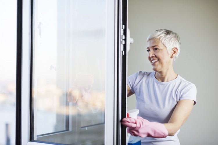 Mature woman cleaning home, washing windows